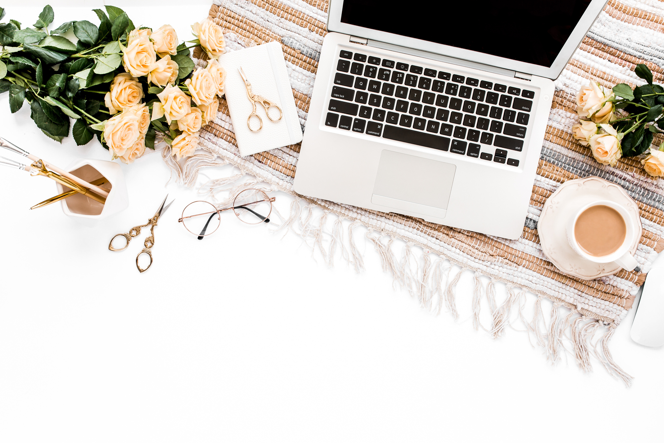 Woman workspace with computer, pink and beige roses flowers bouquet, accessories, diary, glasses on white background. Lay Flat home office desk. Top view feminine background.